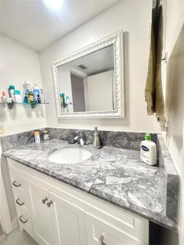 a bathroom with a granite countertop sink and a mirror