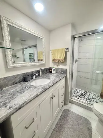 a bathroom with a granite countertop sink a mirror and shower