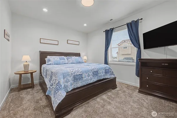 a bedroom with a bed and a flat tv screen on dresser