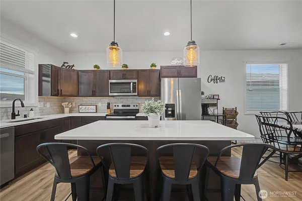 a kitchen with a dining table chairs stainless steel appliances and cabinets