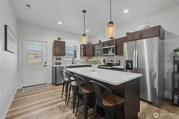 a kitchen with stainless steel appliances a table chairs refrigerator and microwave