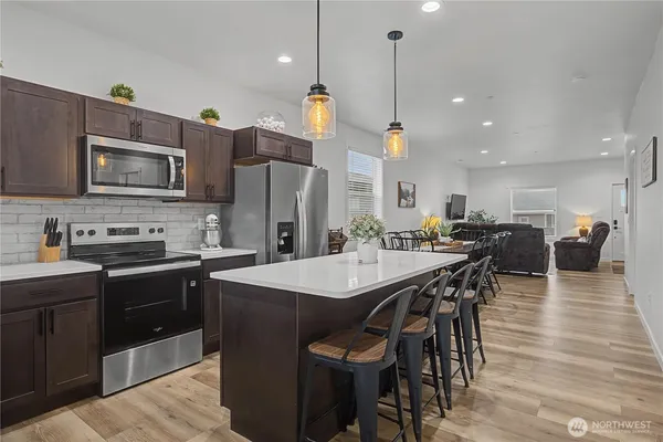 a kitchen with stainless steel appliances a stove a sink a refrigerator a dining table and chairs