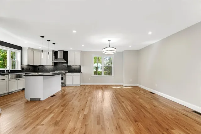 a large kitchen with hardwood floor sink stainless steel appliances and cabinets