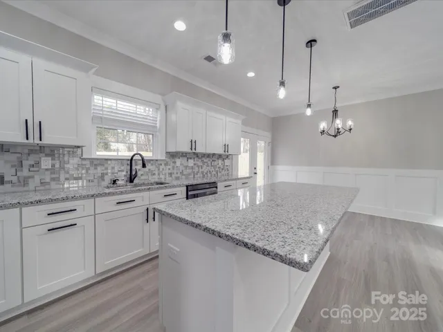 a kitchen with stainless steel appliances granite countertop a sink a stove a dining table and chairs