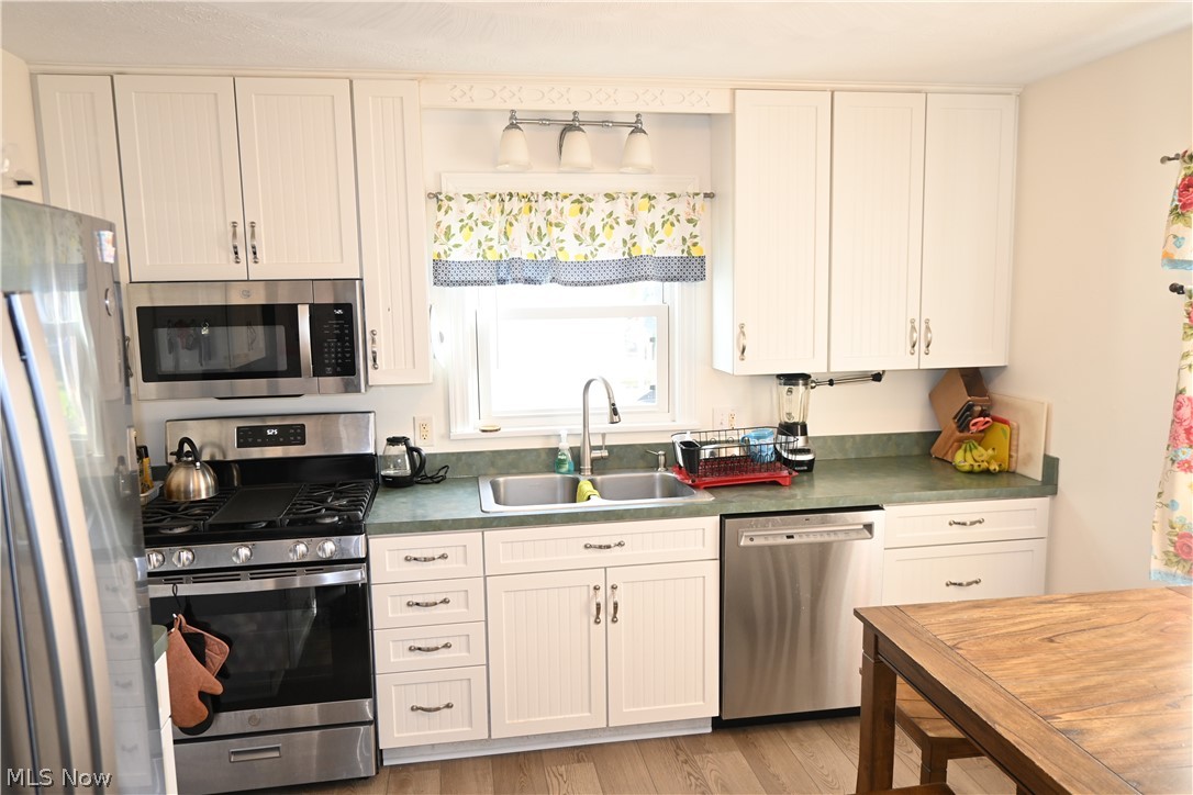 94 North 5th Street Rittman, OH 44270 - Photo 2 of 27 Kitchen with stainless steel appliances, green countertops, wood-style flooring, and white cabinets