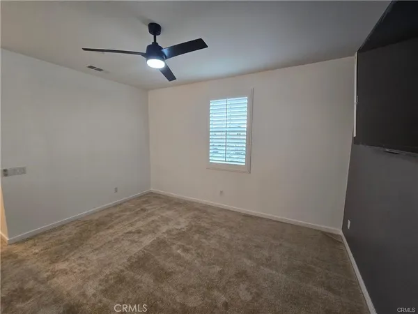 an empty room with ceiling fan and windows