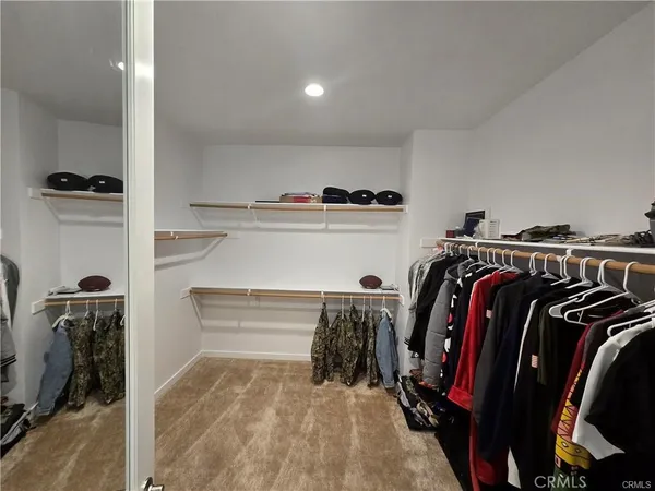 a view of walk in closet with clothes and shoes