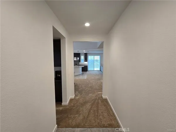 a view of a hallway with wooden floor and kitchen