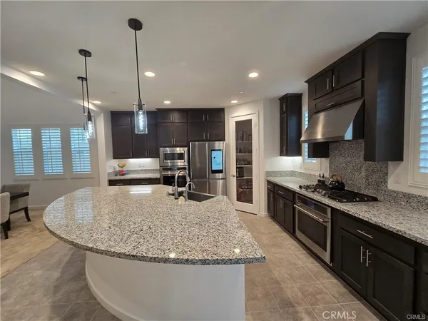 a kitchen with stainless steel appliances granite countertop a sink a stove a refrigerator and a wooden cabinets