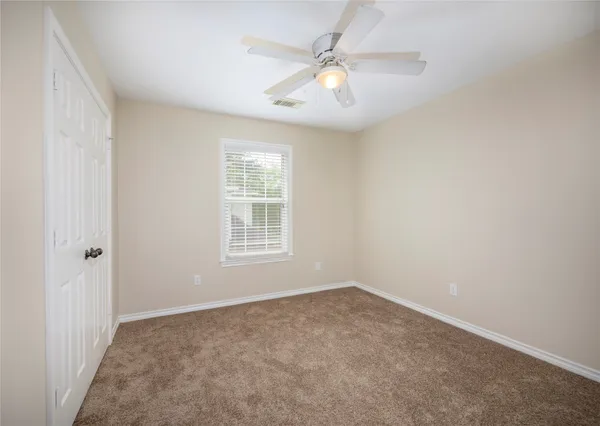 an empty room with windows and fan
