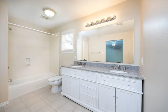 a bathroom with a granite countertop sink a toilet and a bathtub
