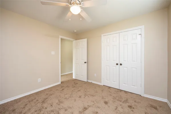 a view of an empty room with a chandelier fan