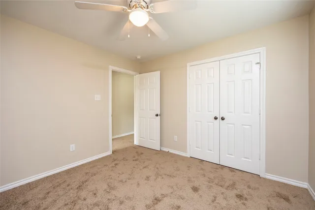 a view of an empty room with a chandelier fan