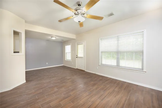 a view of an empty room with a window and wooden floor