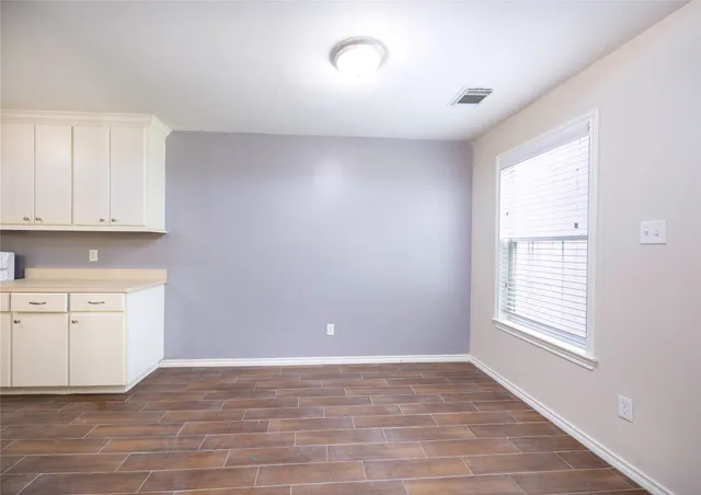 a view of an empty room with a window and a kitchen