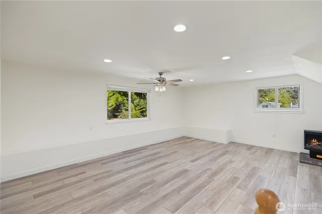 an empty room with wooden floor chandelier fan and windows