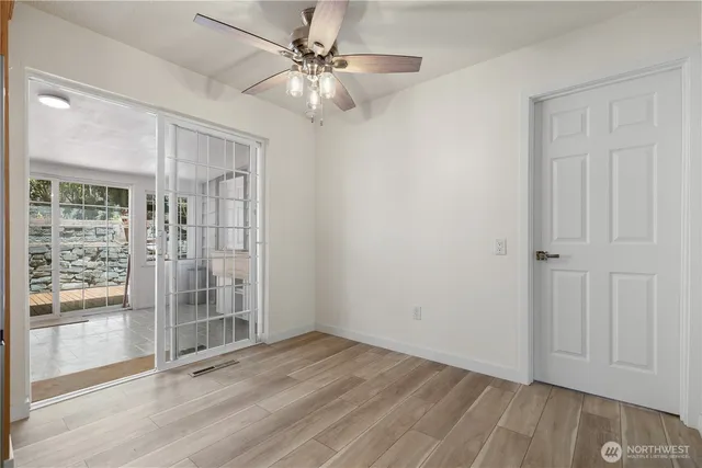 an empty room with wooden floor fan and windows