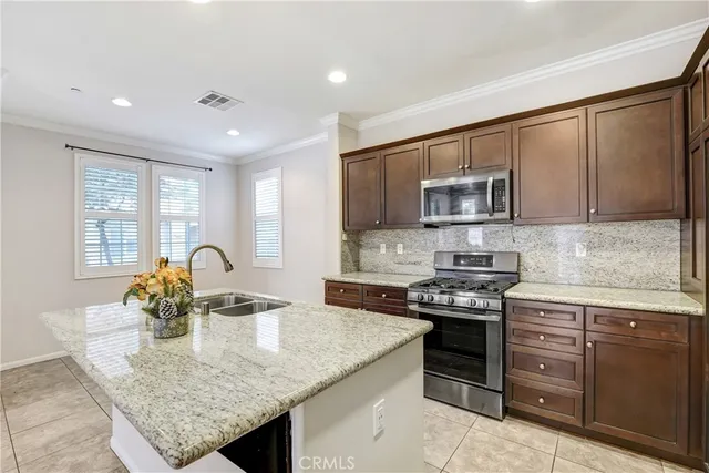 a kitchen with stainless steel appliances granite countertop a stove a sink dishwasher a microwave oven with a dining table and chairs