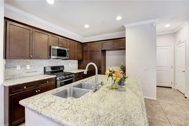 a kitchen with kitchen island granite countertop a sink a stove and cabinets