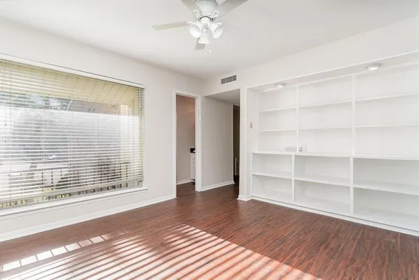 a view of an empty room with a window and wooden floor