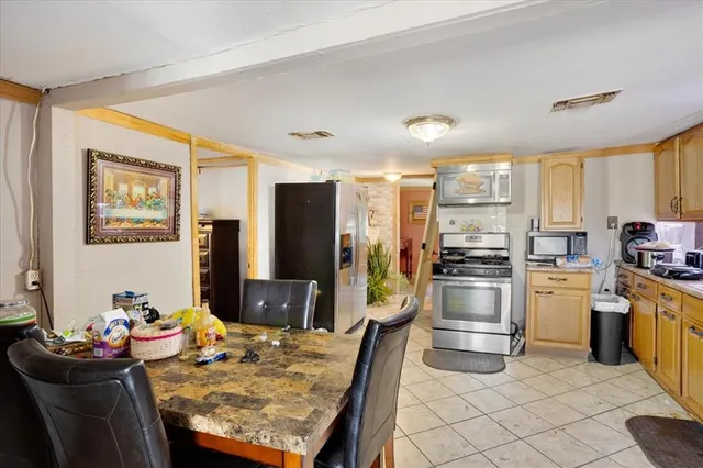 a kitchen with stainless steel appliances kitchen island granite countertop a refrigerator stove top oven dining table and chairs