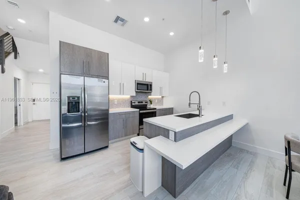 a kitchen with a refrigerator a sink and a stove top oven with wooden floor