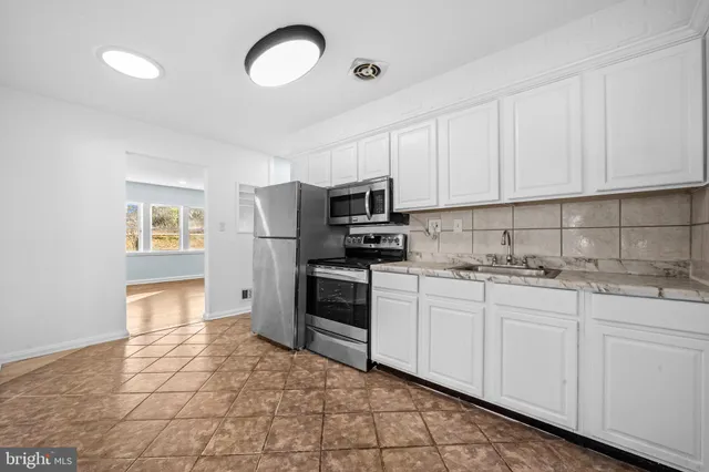 a kitchen with granite countertop a stove top oven sink and cabinets
