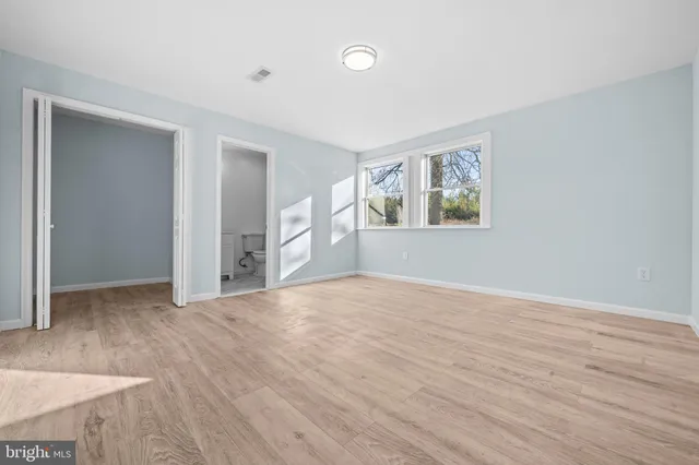 an empty room with wooden floor and windows