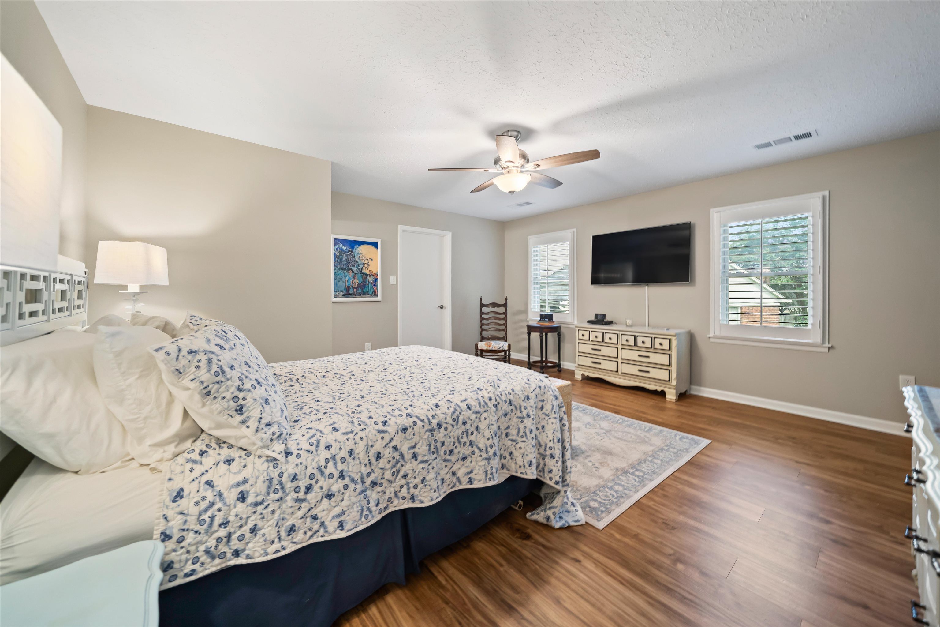 6943 Fords Station Road, Unit 64 Germantown, TN 38138 - Photo 26 of 30 Spacious bedroom featuring wood-finish flooring, two windows with white plantation shutters, a ceiling fan with integrated lighting, and neutral wall tones