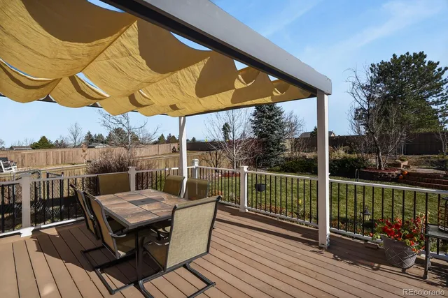 a view of a patio with table and chairs a barbeque with wooden floor and fence