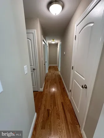 an empty room with wooden floor chandelier fan and windows