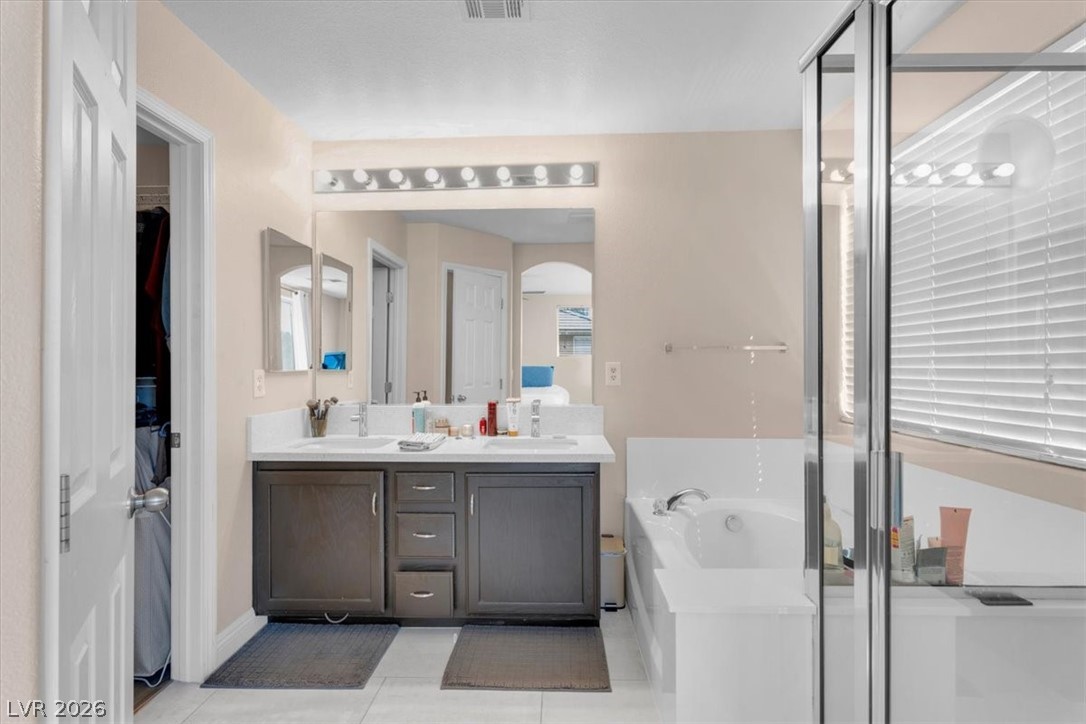 1019 Garnet Ridge Court Las Vegas, NV 89123 - Photo 16 of 34 Full bath featuring double vanity, light tile patterned floors, a stall shower, and a garden tub