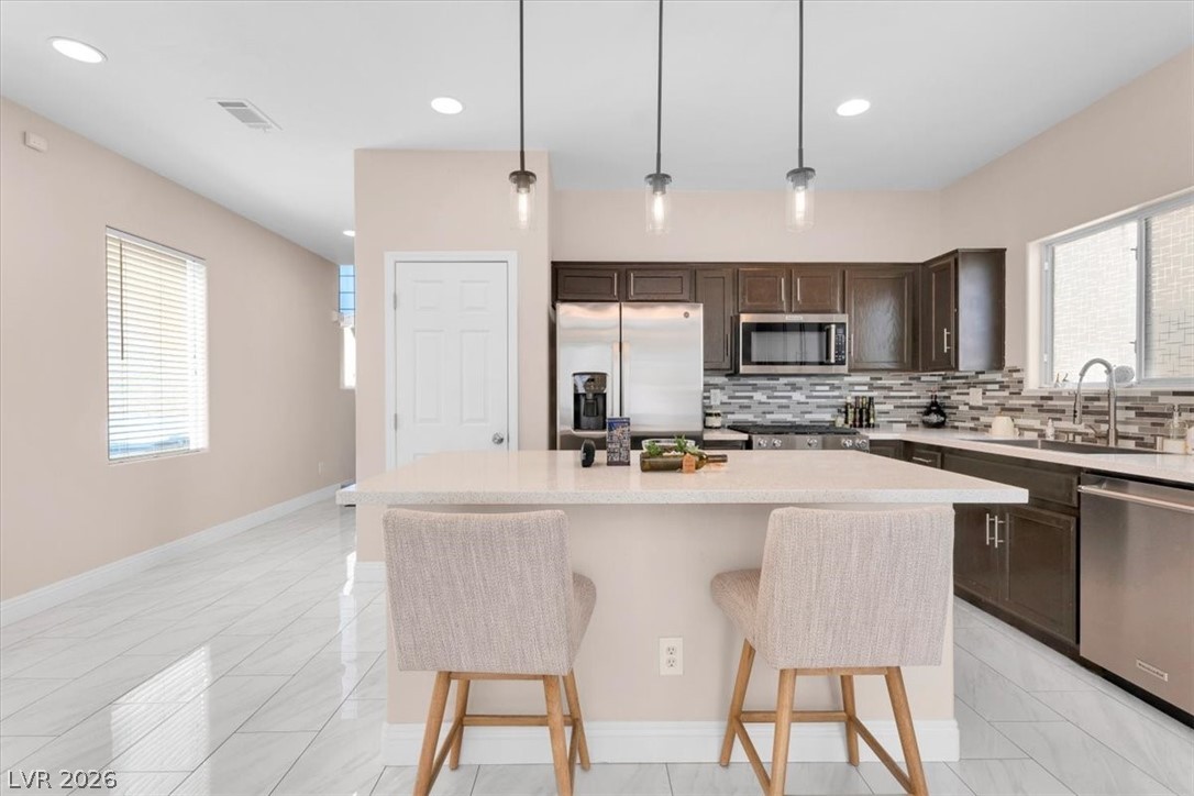 1019 Garnet Ridge Court Las Vegas, NV 89123 - Photo 4 of 34 Kitchen featuring dark wood finish cabinetry, stainless steel appliances, a kitchen island, a breakfast bar area, and decorative backsplash