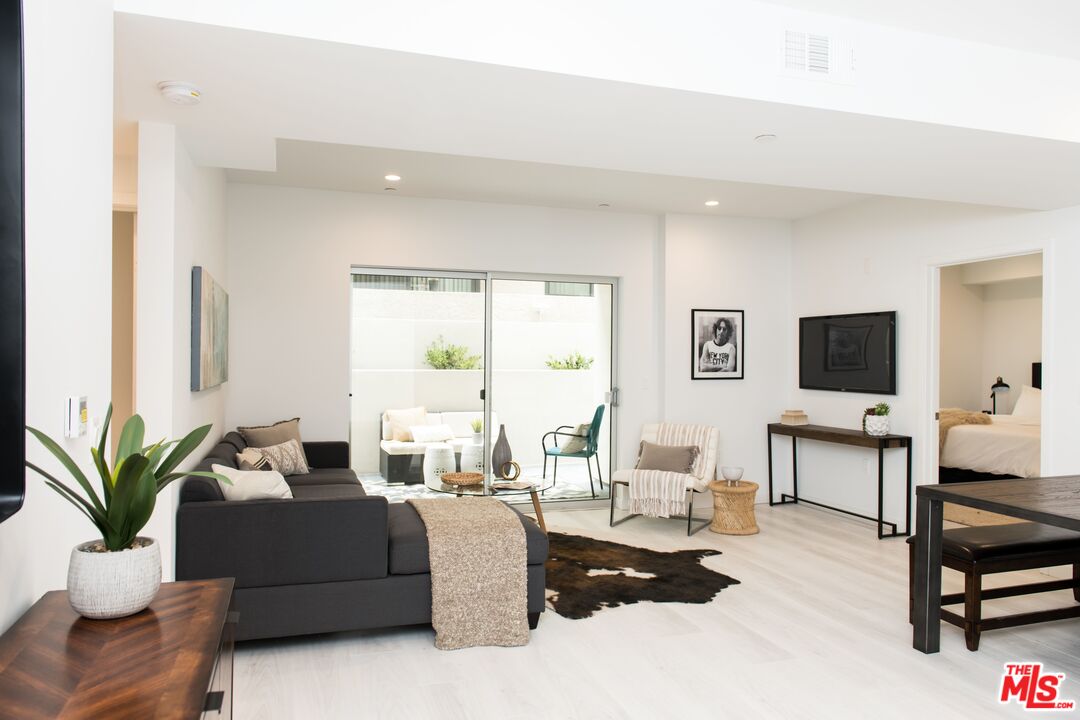 625 South Barrington Avenue, Unit 110 Los Angeles, CA 90049 - Photo 3 of 17 a living room with furniture a large window and a flat screen tv