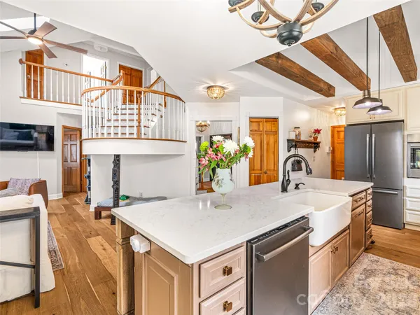 a open kitchen with stainless steel appliances granite countertop a sink and dishwasher a refrigerator with wooden floor