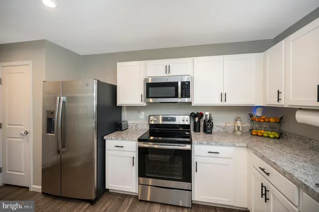 a kitchen with refrigerator a microwave a sink and cabinets