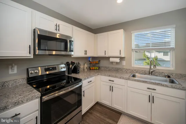 a kitchen with granite countertop a sink dishwasher a stove and a microwave oven with cabinets