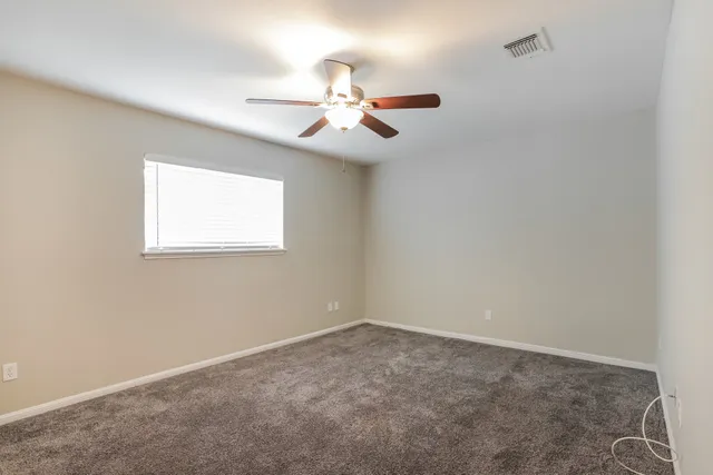 an empty room with a window and a fan