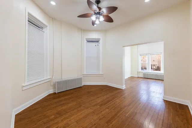 a view of an empty room with a window and wooden floor