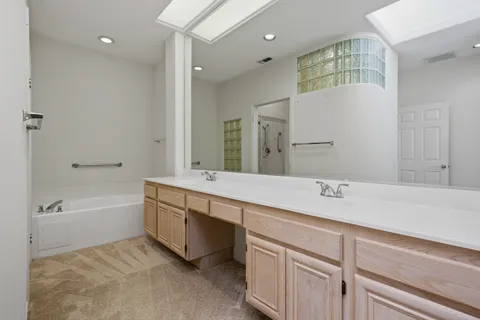 a spacious bathroom with a tub sink and mirror