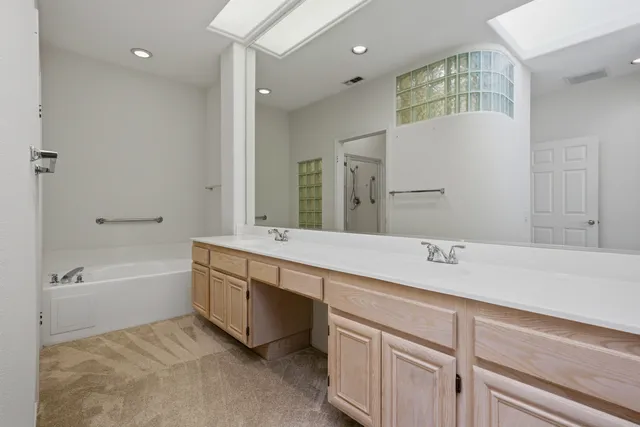 a spacious bathroom with a tub sink and mirror