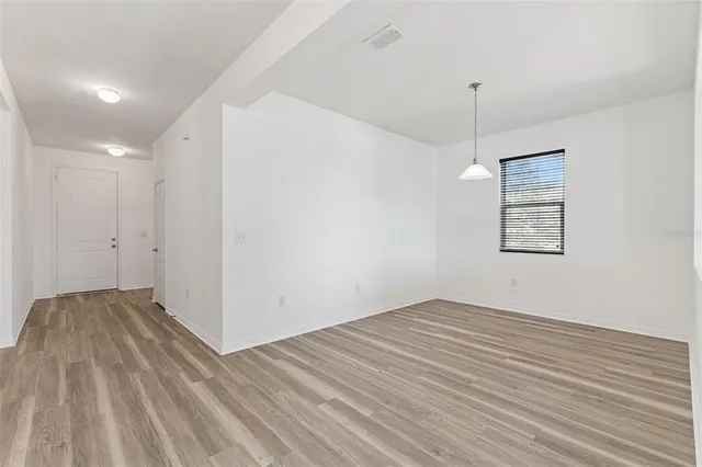a view of an empty room with window and wooden floor