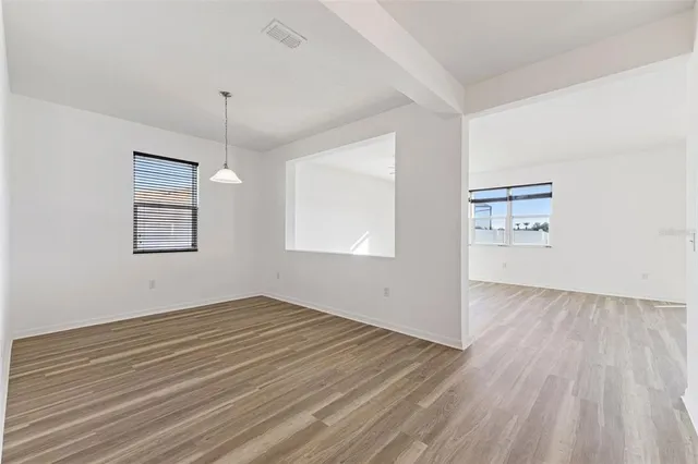 an empty room with wooden floor windows and ceiling fan