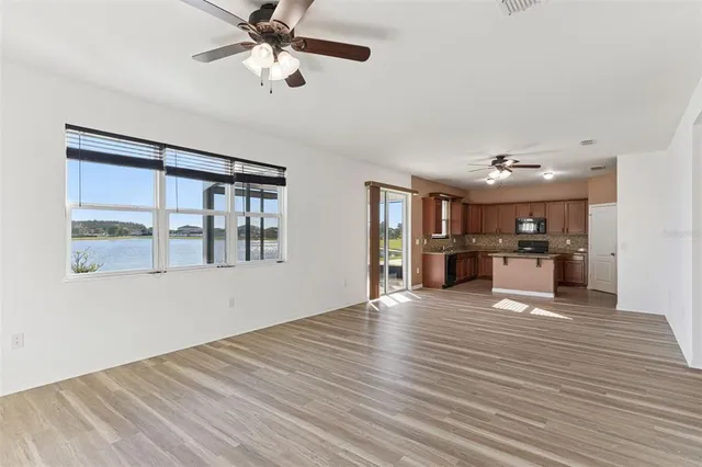 a view of an empty room with kitchen and window