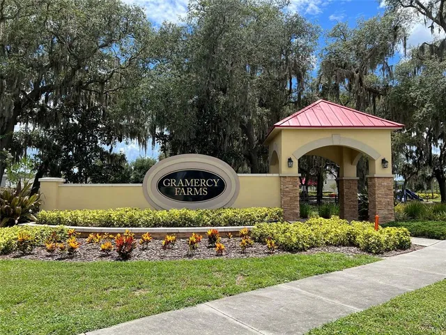 a view of a white house in a big yard with palm trees