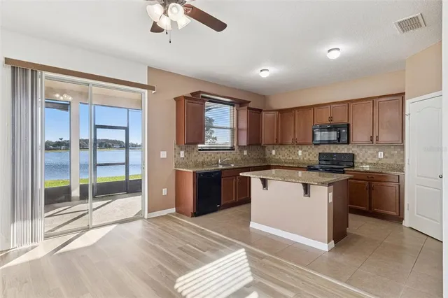 a view of an empty room with wooden floor and a ceiling fan