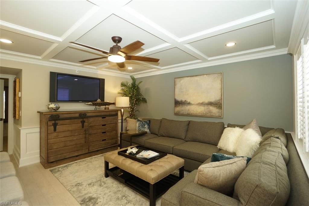 480 5th Street South, Unit 102 Naples, FL 34102 - Photo 4 of 24 a living room with furniture a flat screen tv and a ceiling fan