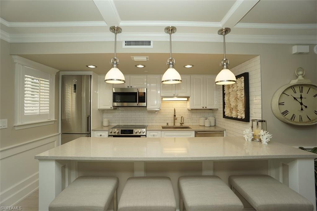 480 5th Street South, Unit 102 Naples, FL 34102 - Photo 8 of 24 a kitchen with a sink a clock and cabinets