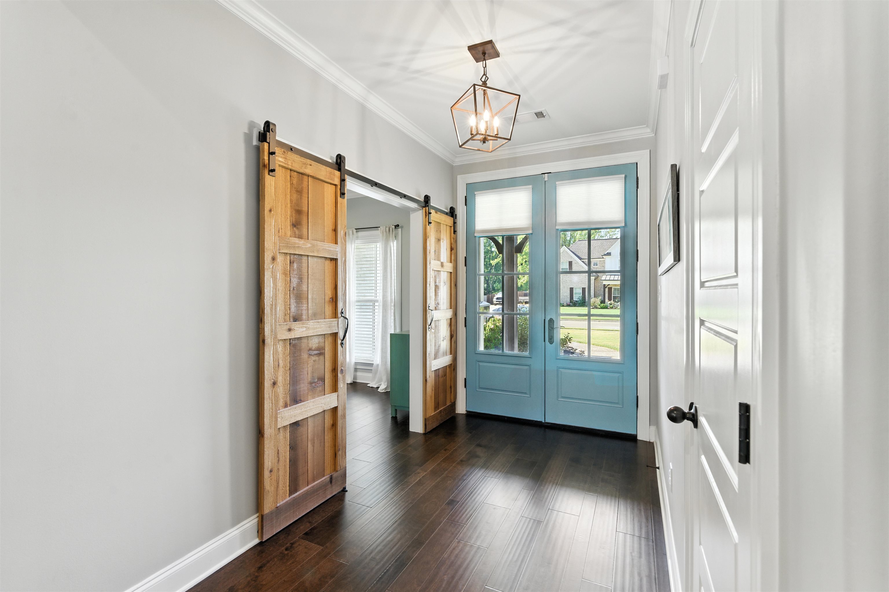 46 Cedar Ridge Cove Atoka, TN 38004 - Photo 5 of 40 Doorway to outside featuring crown molding, wood finished floors, a barn door, and a chandelier
