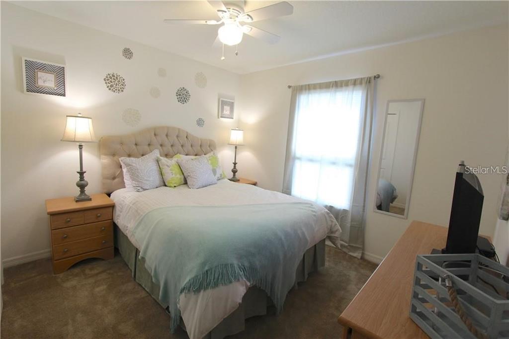 957 Emerald Green Court Kissimmee, FL 34746 - Photo 14 of 29 a bedroom with a bed and a flat tv screen on dresser